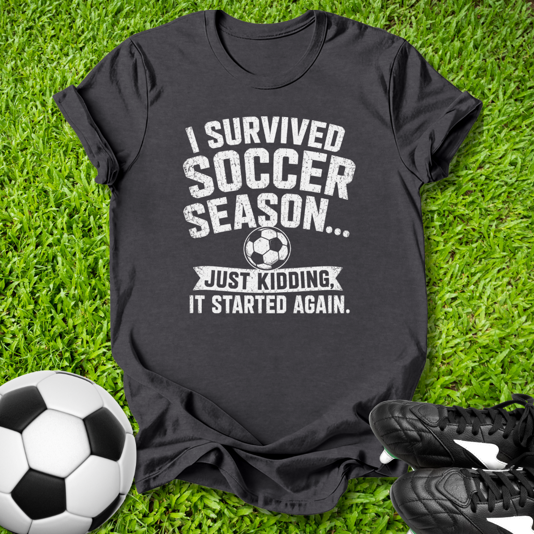 Black t-shirt with humorous soccer text on grass with soccer ball and shoes
