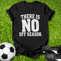 Black t-shirt with 'There is no off season.' text on grass with soccer ball and shoes.