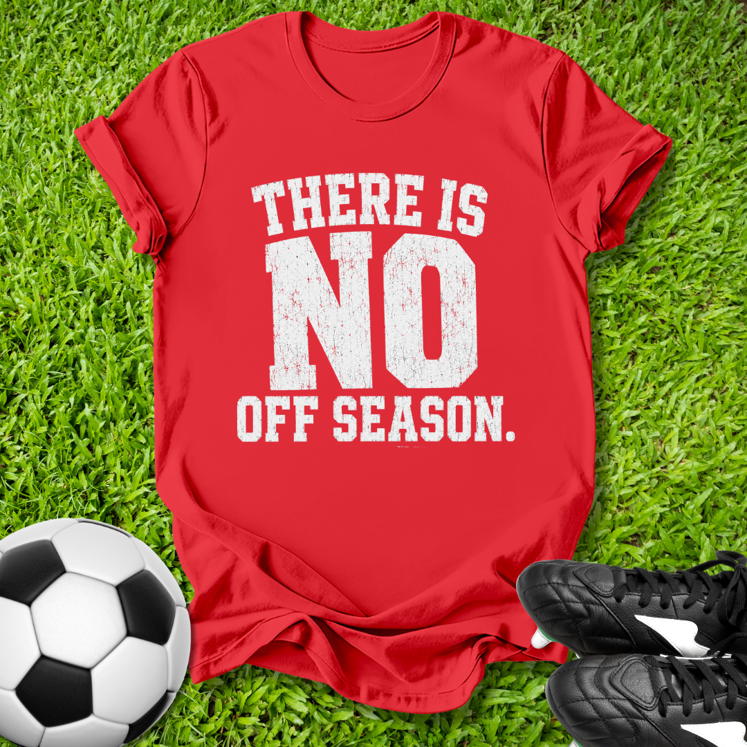 Red t-shirt with 'There is no off season' text on grass with soccer ball and shoes.