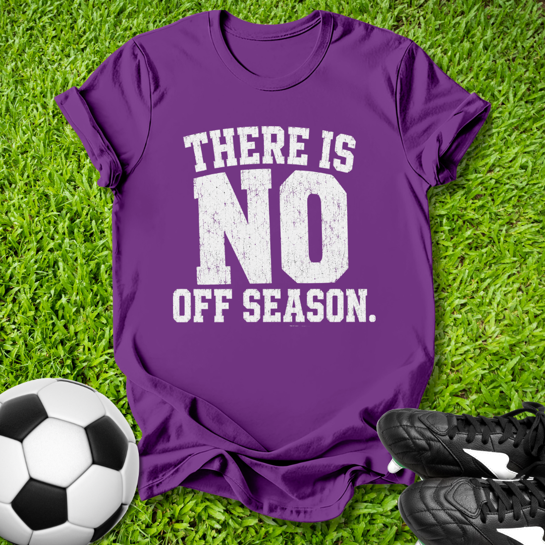 Purple t-shirt with 'There is no off season' text on grass with soccer ball and shoes.
