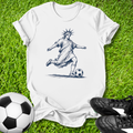 White t-shirt with a graphic of the Statue of Liberty playing soccer on grass with soccer ball and shoes.