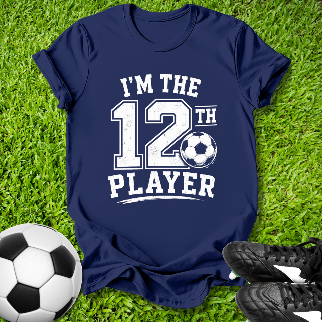 Navy blue t-shirt with 'I'm the 12th Player' text on grass with soccer ball and shoes.