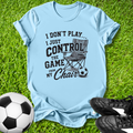 Light blue t-shirt with a graphic and text on grass with soccer ball and shoes.