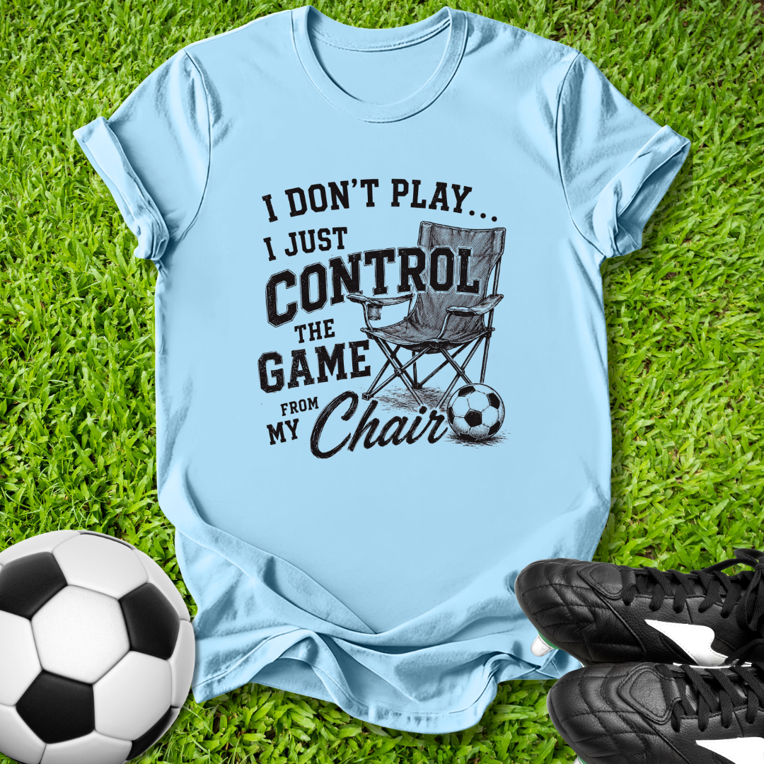 Light blue t-shirt with a graphic and text on grass with soccer ball and shoes.