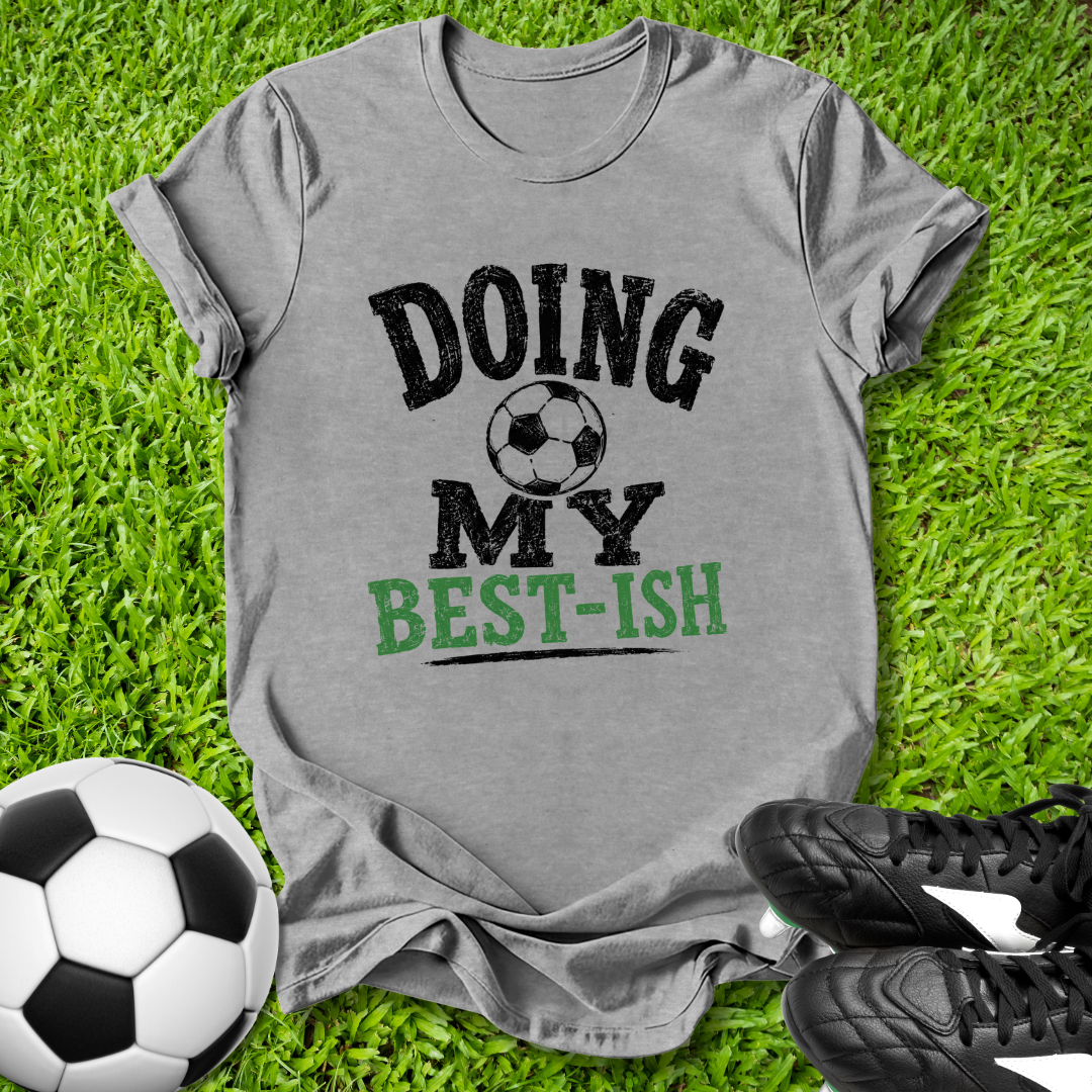 Gray t-shirt with 'Doing My Best-ish' text on grass with soccer ball and shoes