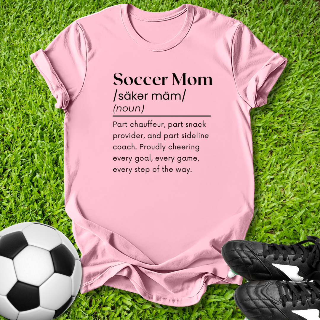Pink t-shirt with 'Soccer Mom' definition on grass with soccer ball and shoes