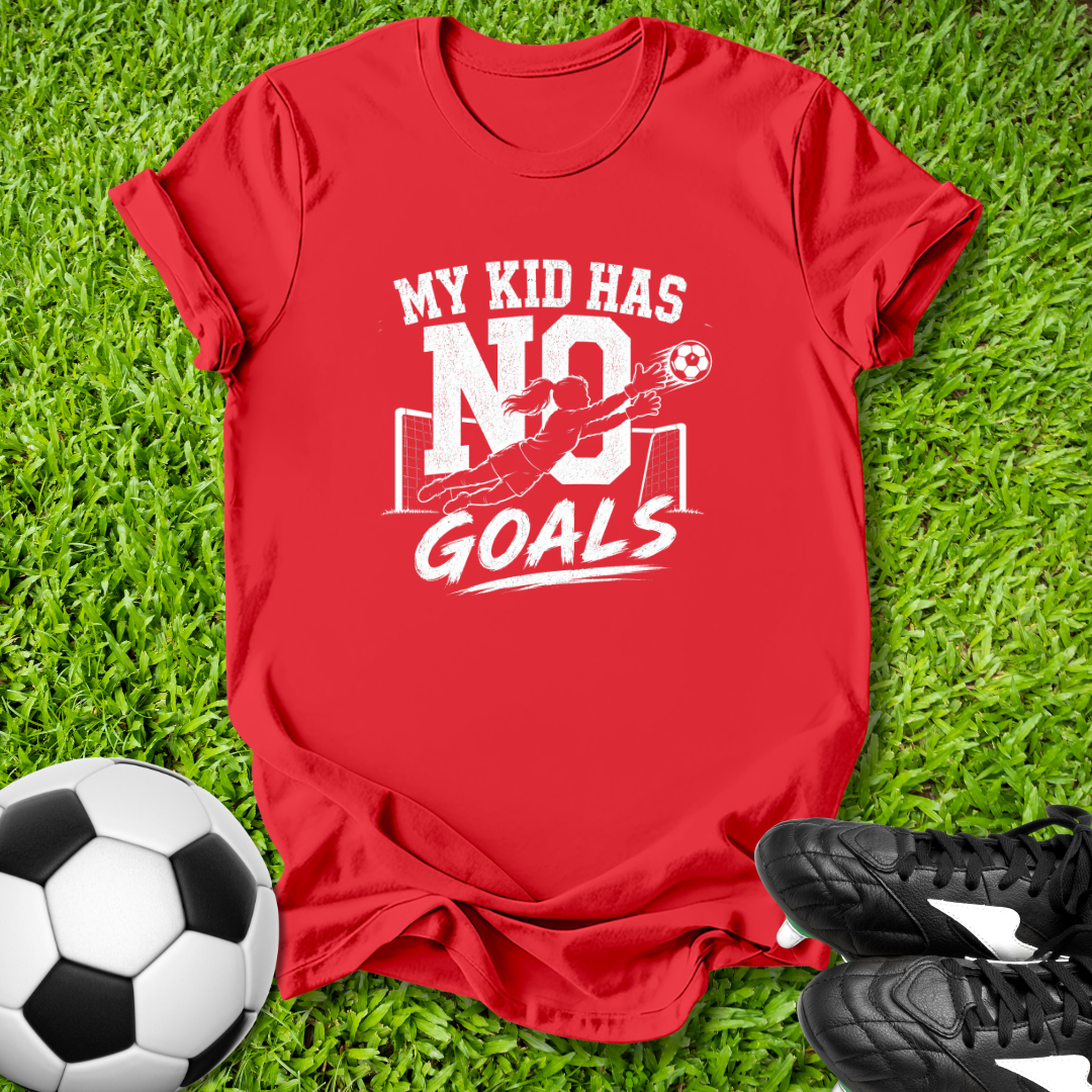 Red t-shirt with 'My kid has no goals' text on grass with soccer ball and shoes