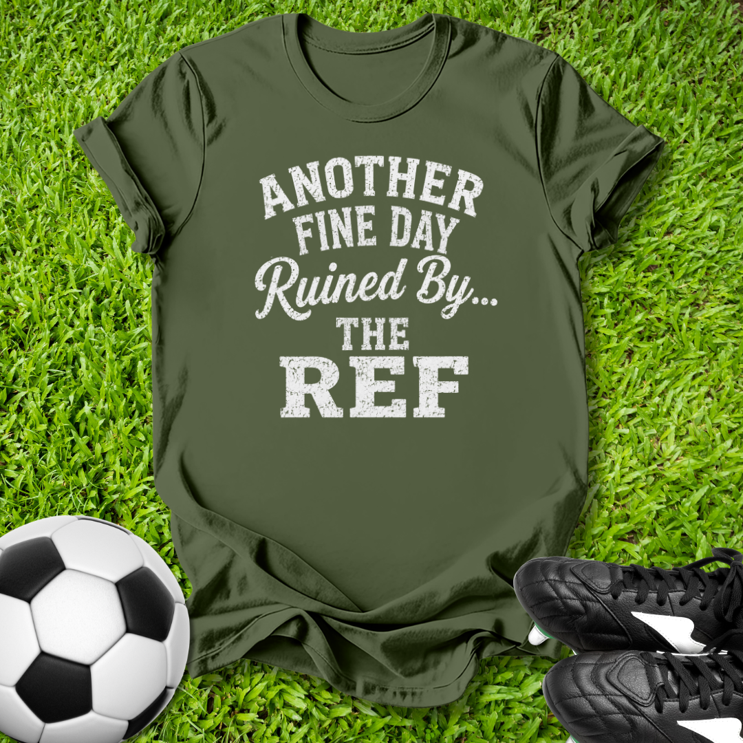Green t-shirt with humorous text on grass with soccer ball and shoes