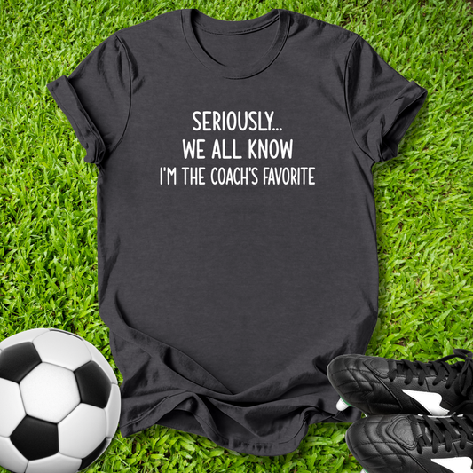 Black t-shirt with humorous text on grass with soccer ball and shoes