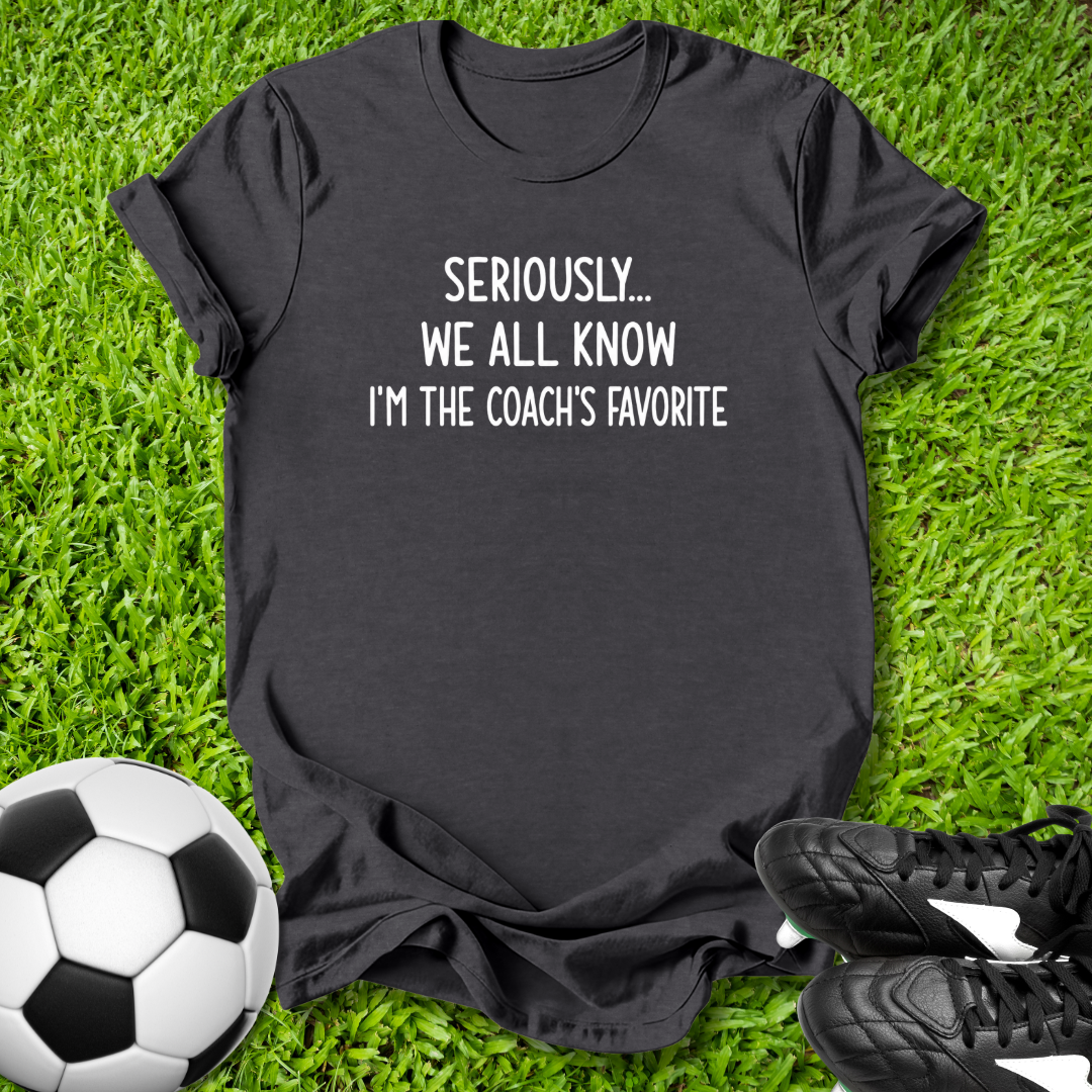 Black t-shirt with humorous text on grass with soccer ball and shoes