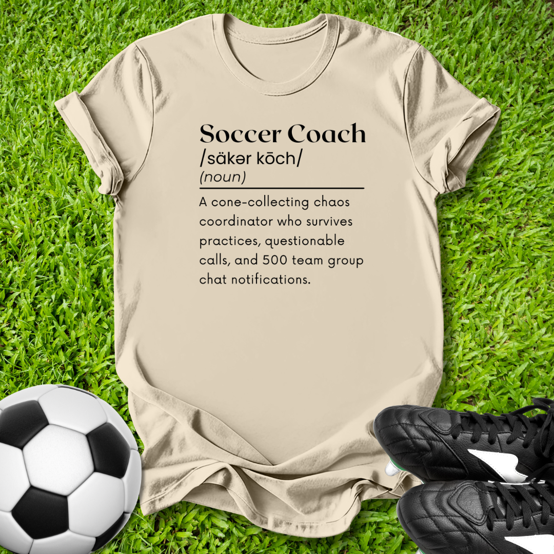 Beige t-shirt with soccer coach definition on grass with soccer ball and shoes