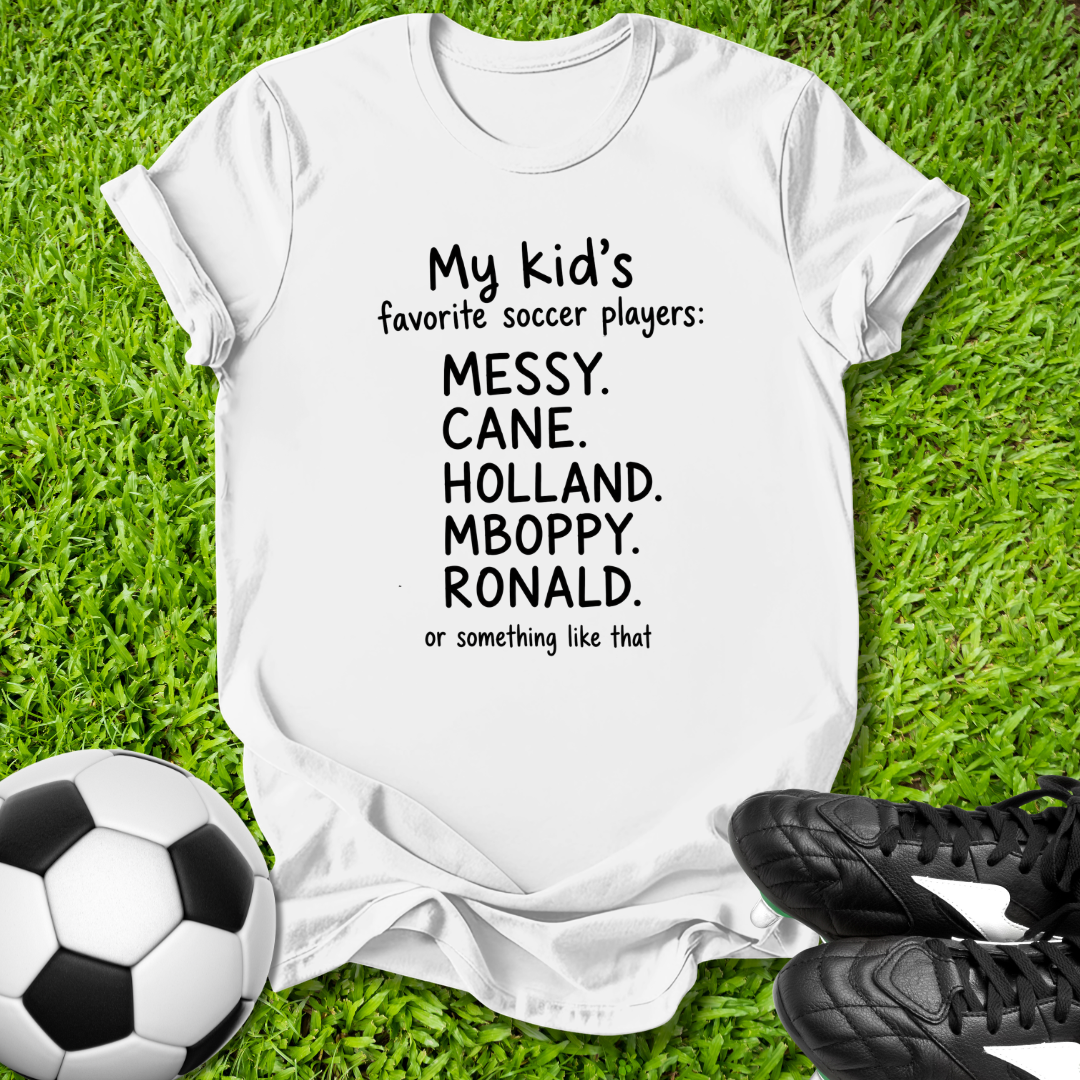 White t-shirt with humorous text on grass with soccer ball and shoes