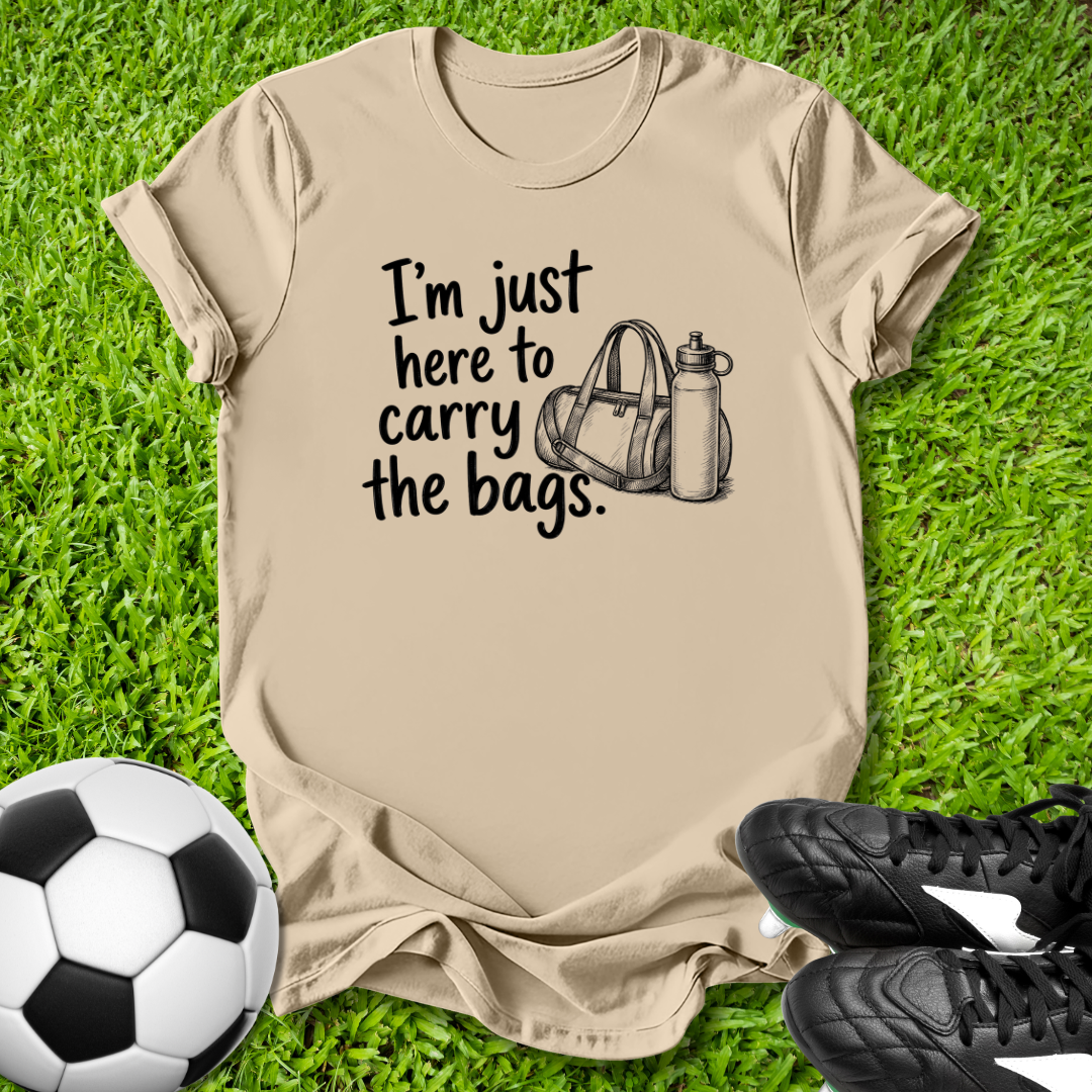 Beige t-shirt with humorous text and graphic on grass with soccer ball and shoes