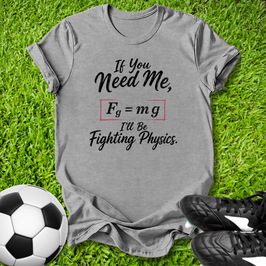 Gray t-shirt with soccer-themed graphic on grass with soccer ball and shoes