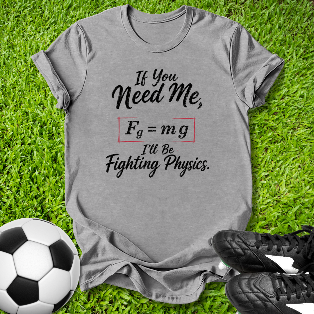 Gray t-shirt with soccer-themed graphic on grass with soccer ball and shoes