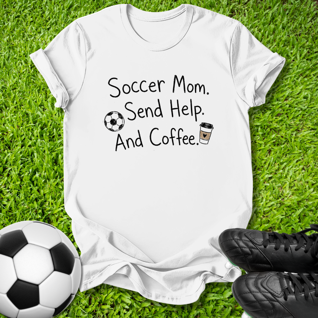 A white graphic t-shirt laid flat on green grass, featuring the text 'Soccer Mom. Send Help.